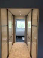 U shapped sliding wardrobe in pearl white glass split into thirds with polished silver frames with end door open