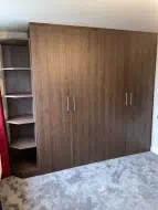 Fitted hinged wardrobe with open end shelves before doors with doors